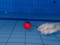 Ein mit Luft gefüllter Ball wird mit einem Löffer unterwasser balanciert